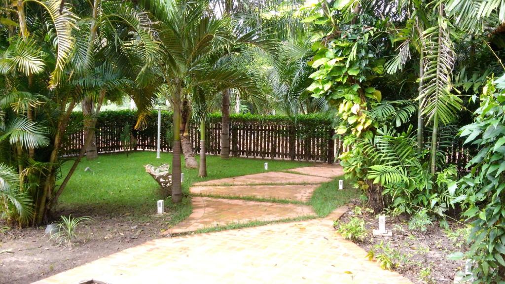 a garden with a fence and a walkway with palm trees at Casa na Faz Real in Teresina