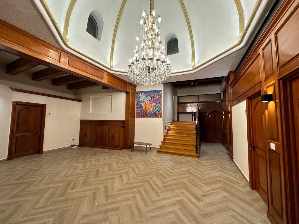 a large room with a chandelier and a hallway at Suites del Jardín Principal in Guanajuato