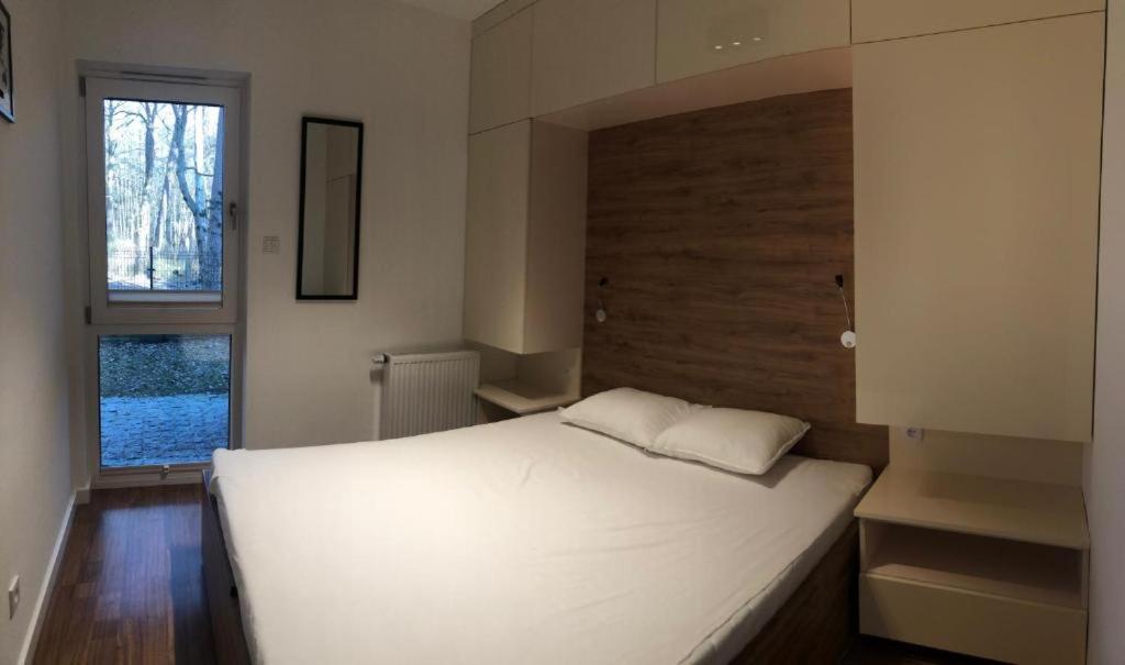 un grand lit blanc dans une chambre avec une fenêtre dans l'établissement Apartament Nad Liwką, à Niechorze