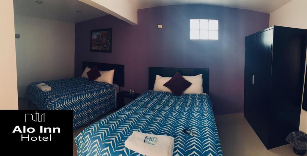 2 letti in una camera con pareti viola di ALO INN Hotel a San Roque