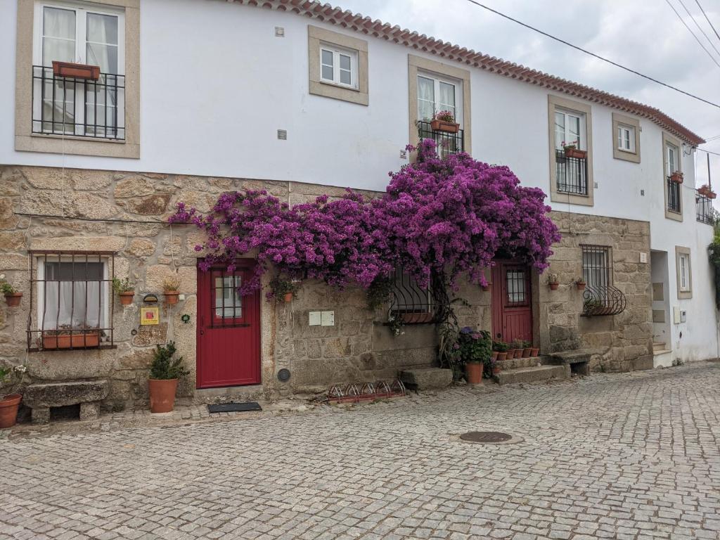 a building with purple flowers on the side of it at Casa do Forno in Salvaterra do Extremo