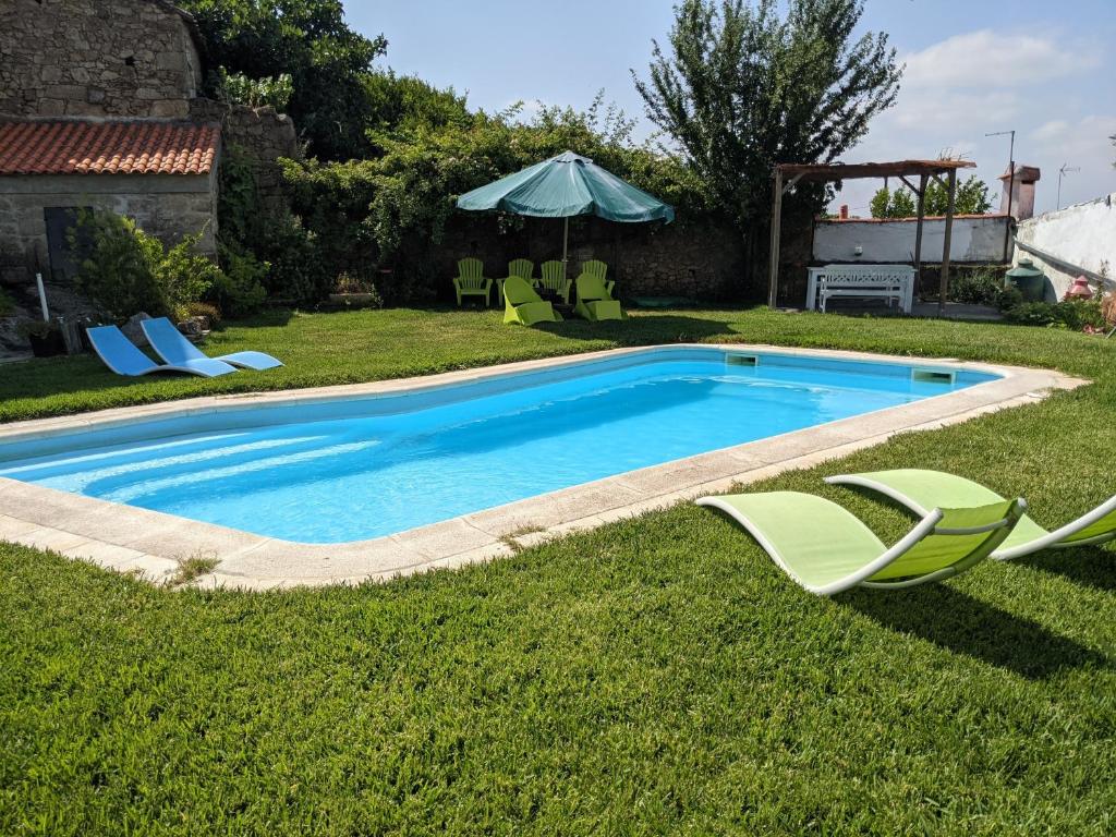 a swimming pool with two lawn chairs and an umbrella at Casa do Forno in Salvaterra do Extremo