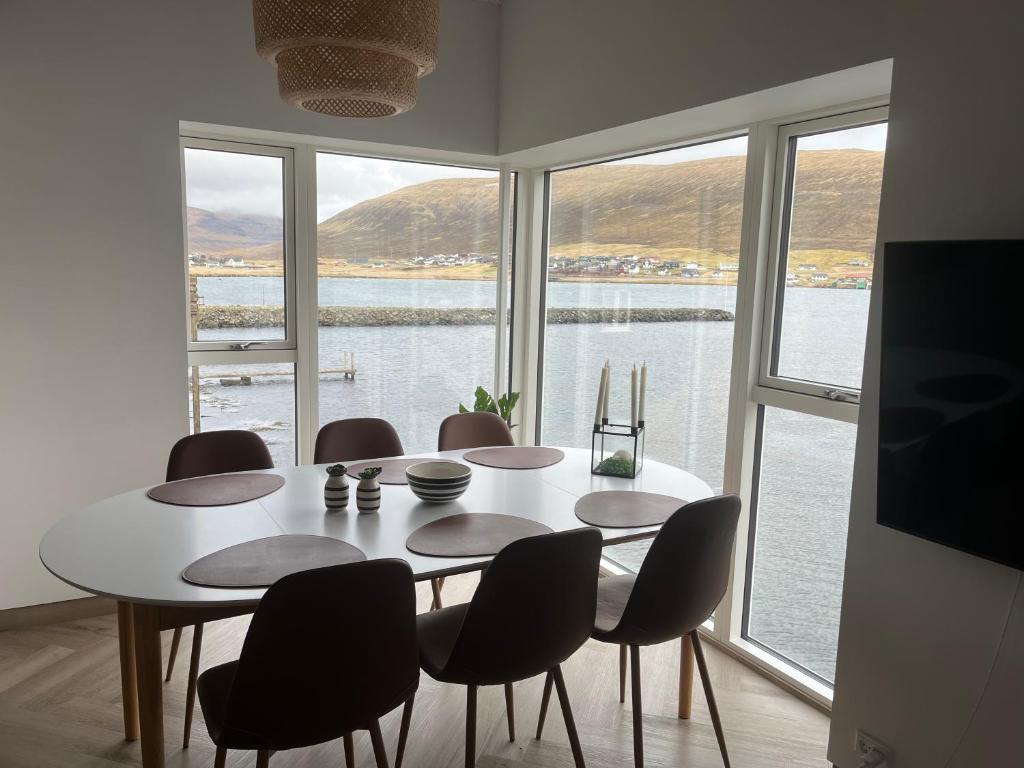 a dining room with a table and chairs and a large window at Brand New Waterfront-Apartment in Hvalvík