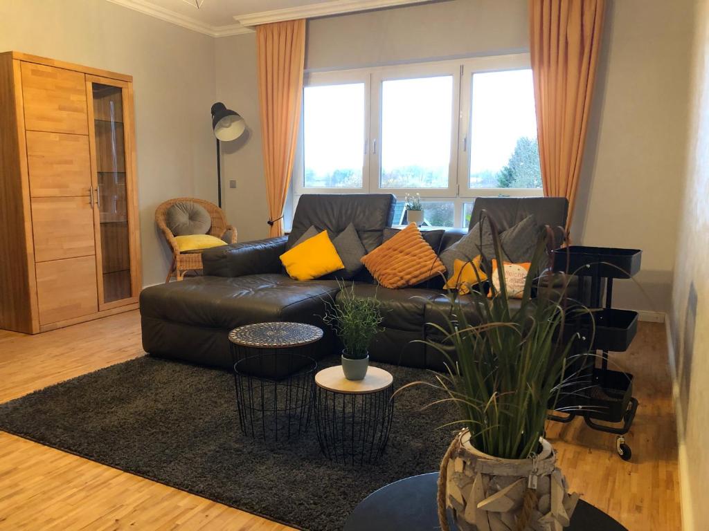 a living room with a black leather couch with yellow pillows at Gemütliches Apartment Garden View in Ramstein-Miesenbach