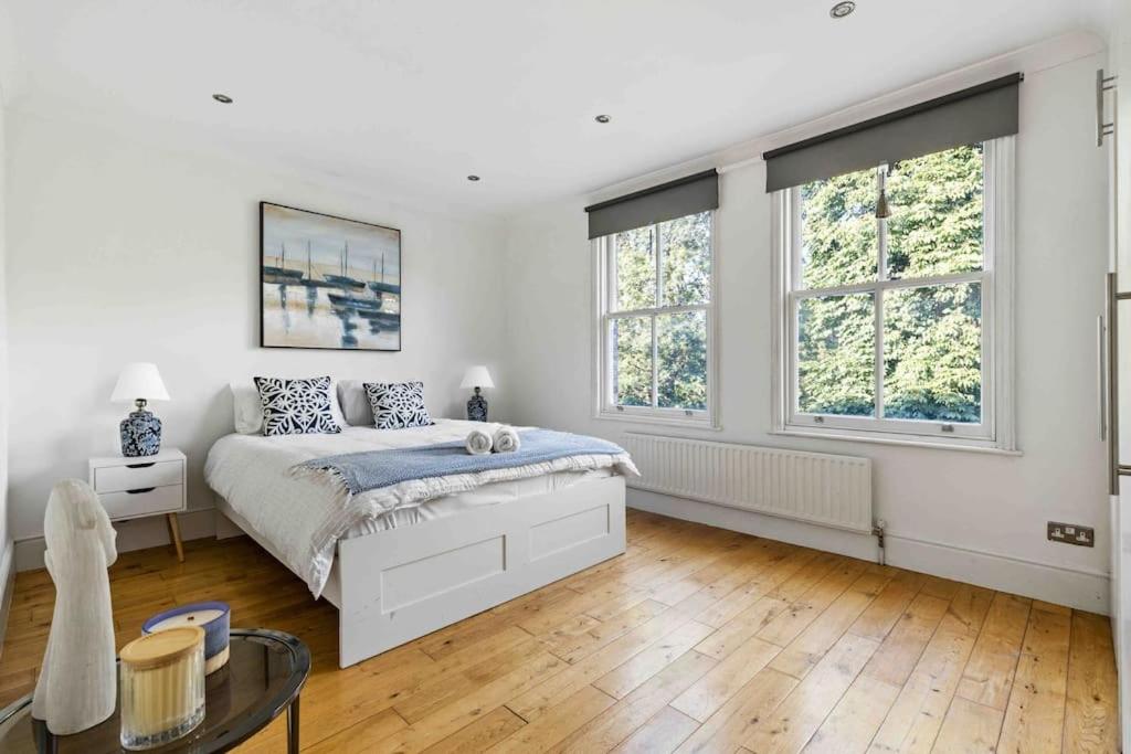a white bedroom with a bed and two windows at Wandsworth house in London