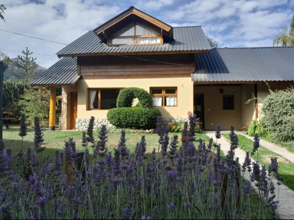 una casa con flores púrpuras delante de ella en Tierras del Sur II en Villa La Angostura