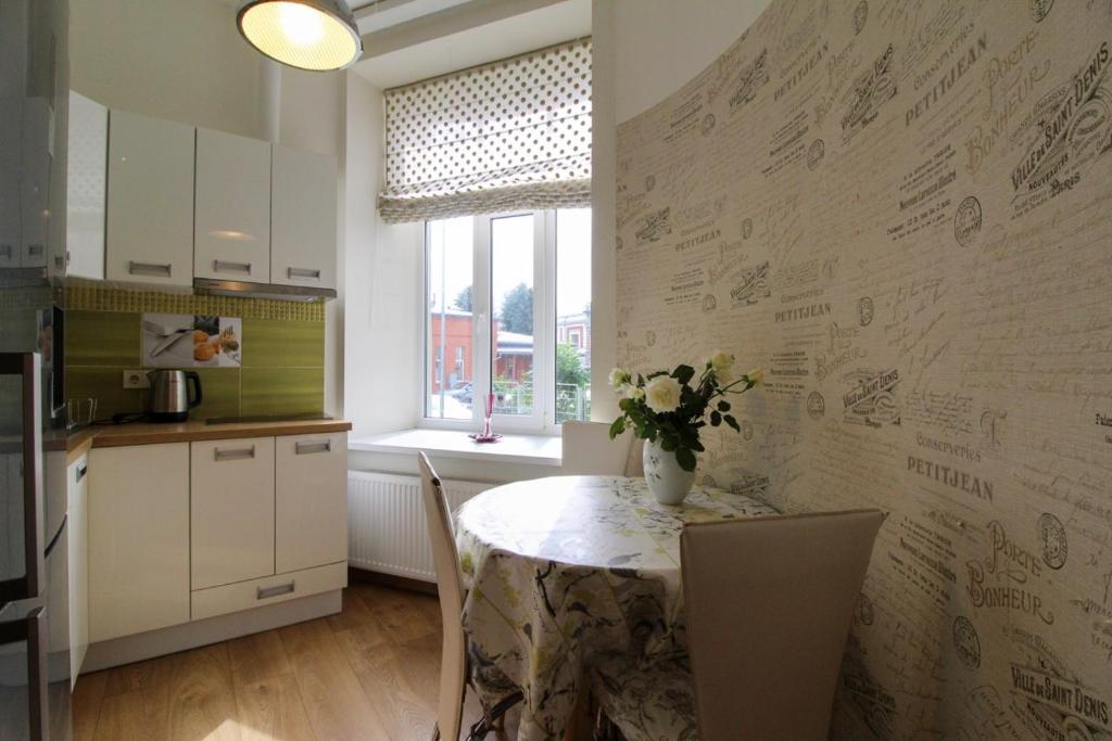 a kitchen with a table with a vase of flowers on it at Great Amber Apartment in Liepāja