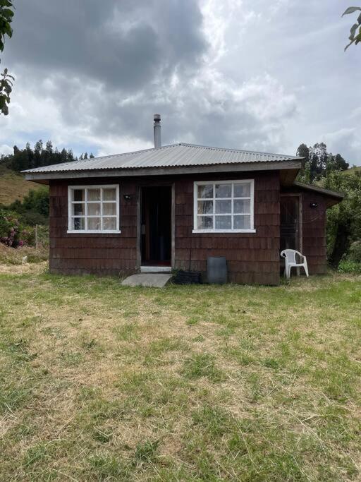 ein kleines Backsteinhaus mit einem weißen Stuhl im Hof in der Unterkunft Cabaña 4 personas en Calen Rural, Chiloé in Dalcahue