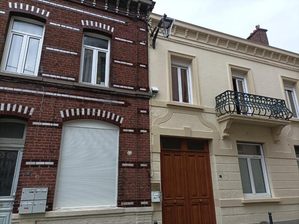 un edificio de ladrillo con puerta roja y balcón en Le Velvet, en Hénin-Beaumont