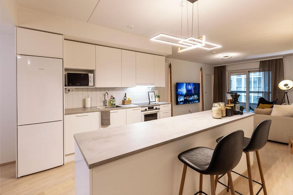 a kitchen with white cabinets and a counter and chairs at Stylish Scandinavian Suite - Sauna, Harbor & Free Parking in Helsinki