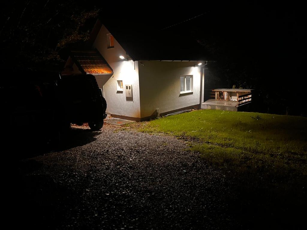 una casa iluminada por la noche con un coche aparcado fuera en ALBAK Green Zone, en Gradačac