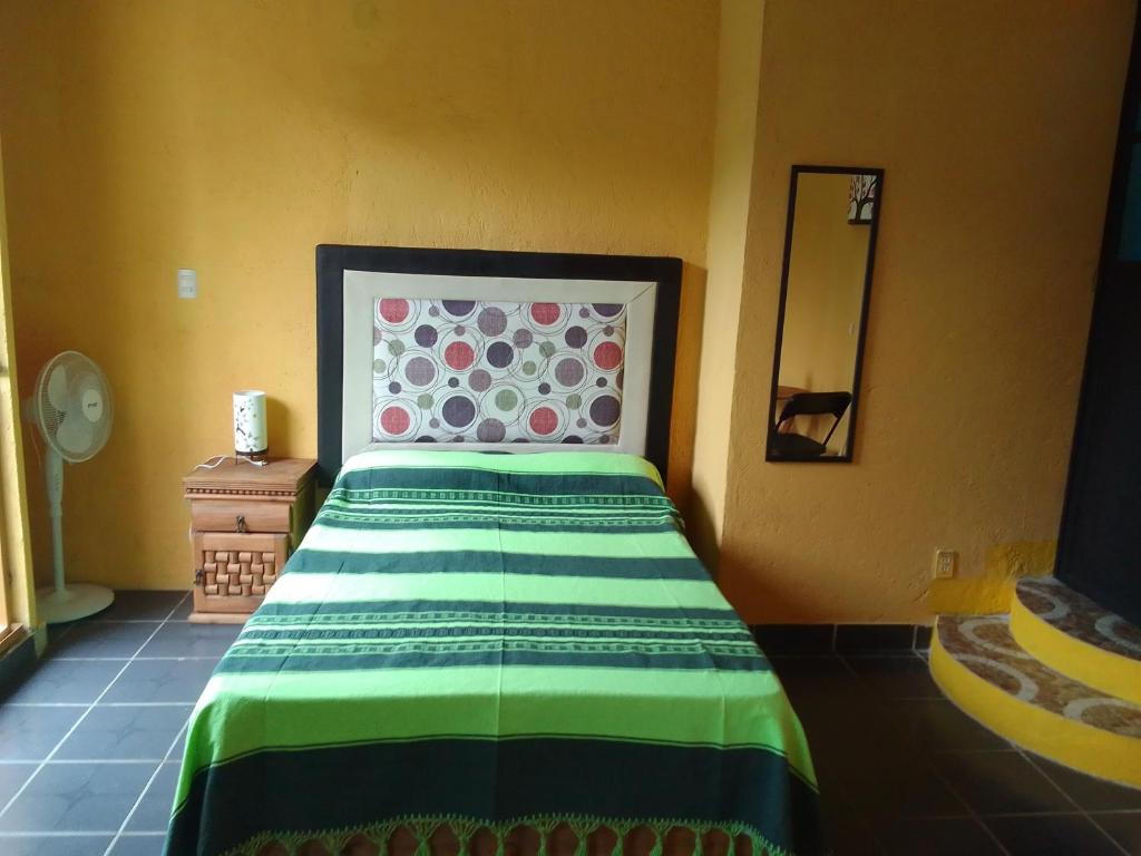 1 dormitorio con 1 cama con manta verde y blanca en Hospedaje Casa Cortés - Recamaras de Descanso en Tepoztlán Mor, en Tepoztlán
