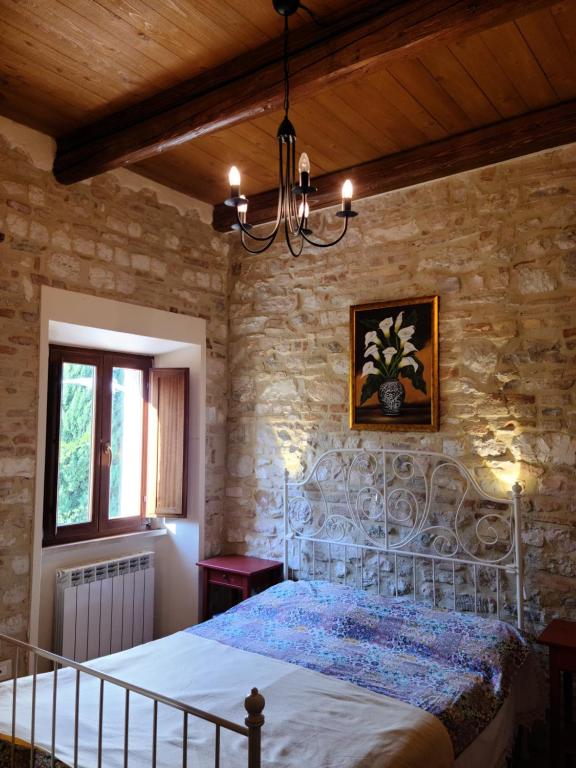 una camera da letto con un letto di metallo in una parete in pietra di Casa Ventura ad Arcevia
