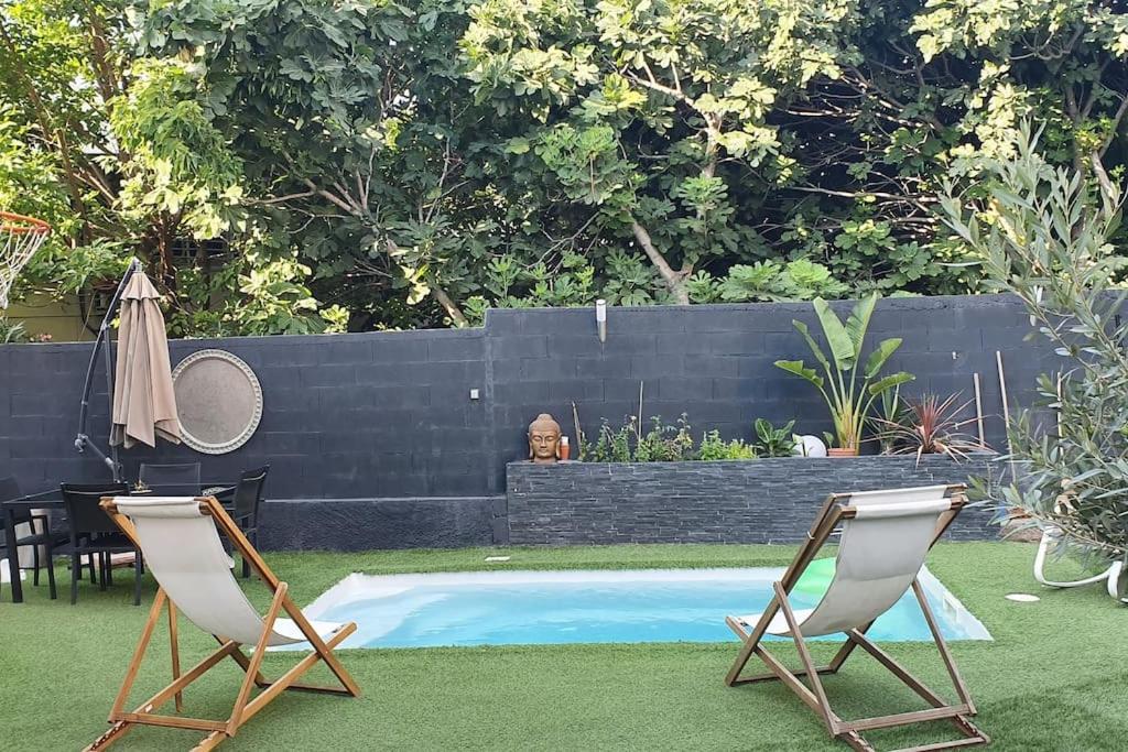 2 sillas y una piscina en el patio trasero en Maisonnette climatisée avec piscine & Spa en Marsella