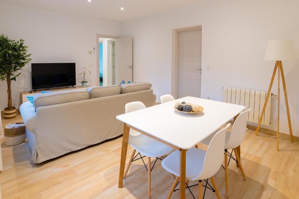 TrendyHomes Granada - moderno apartamento a 15 minutos del centro في غرناطة: غرفة معيشة مع طاولة بيضاء وأريكة