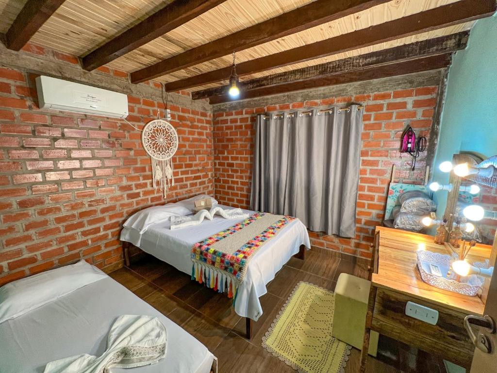 um quarto com uma cama e uma parede de tijolos em Pousada Taruma Challes 02 em Bonito
