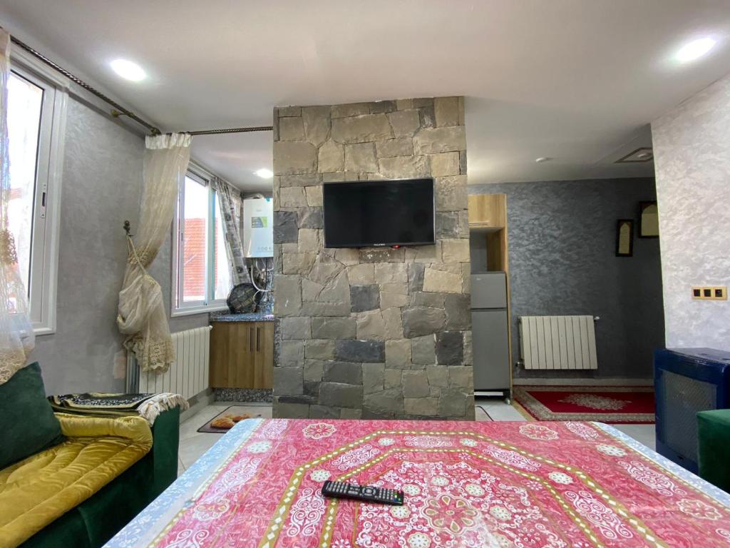 a living room with a tv on a stone wall at la paix in Ifrane