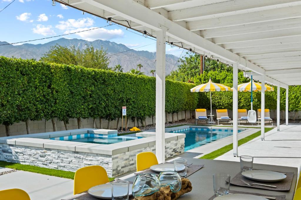 an outdoor patio with a pool and tables and chairs at The Yellow Retreat in Palm Springs
