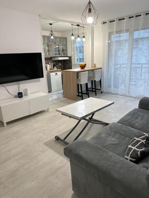 a living room with a couch and a table at Appartement gare Plaisir grignon in Plaisir