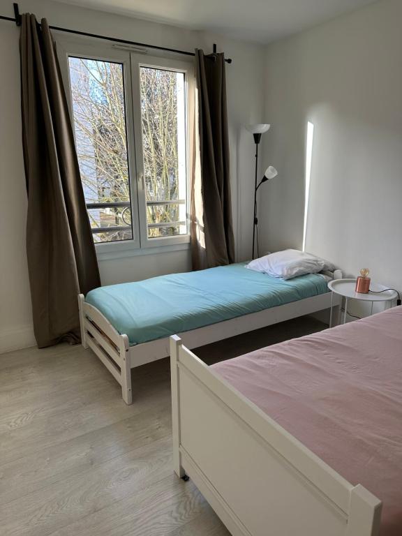 a bedroom with two beds and a window at Appartement gare Plaisir grignon in Plaisir