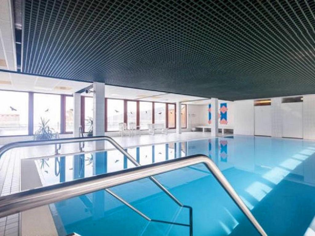 a large swimming pool with blue water in a building at Schwarzwald Auszeit mit Sauna, Pool & Dachterrasse in Sasbachwalden