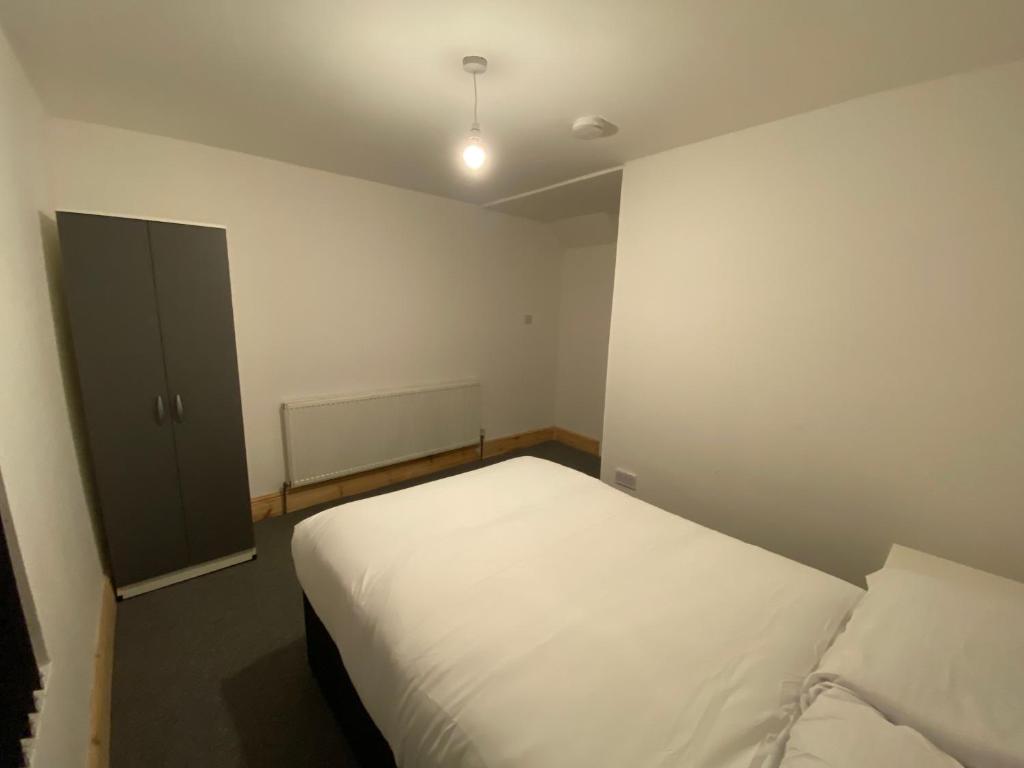 um pequeno quarto com uma cama branca em Spacious 4BR Close to Digbeth em Birmingham
