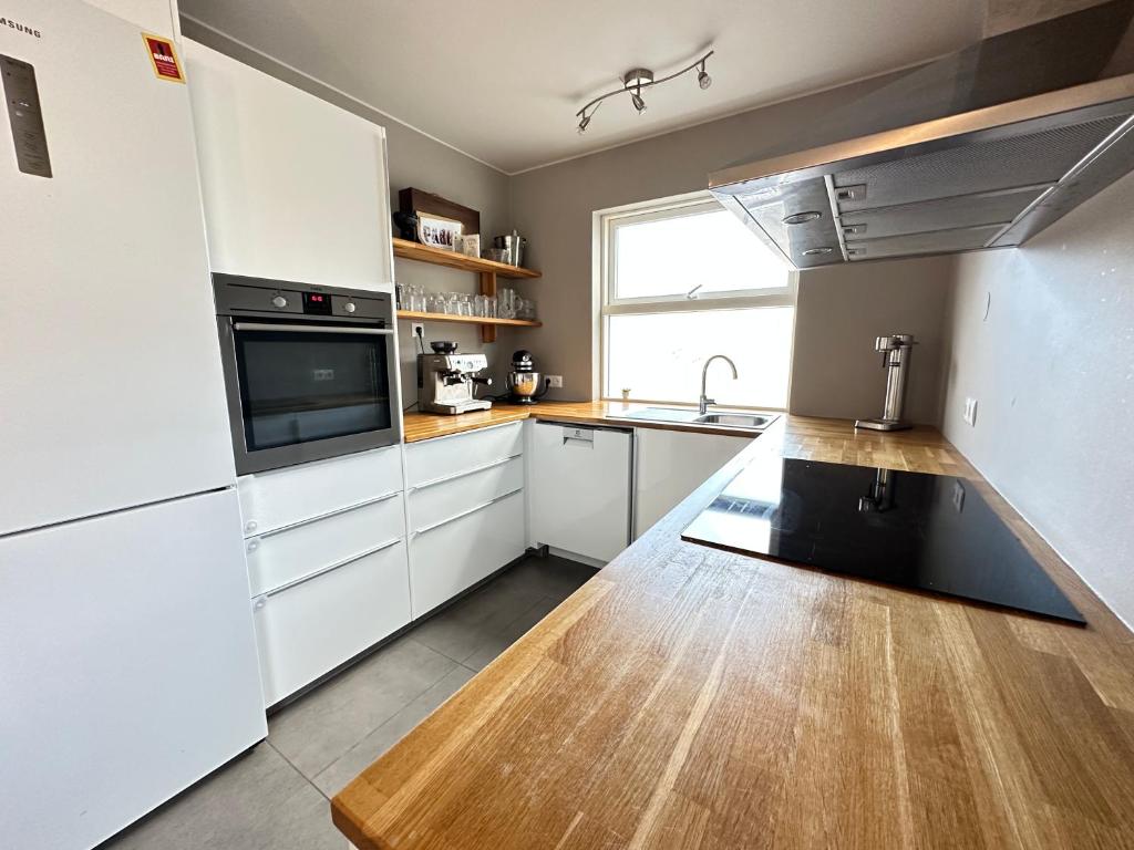 een keuken met witte kasten, een wastafel en een magnetron bij Spacious and family friendly apartment in Kópavogur in Reykjavík