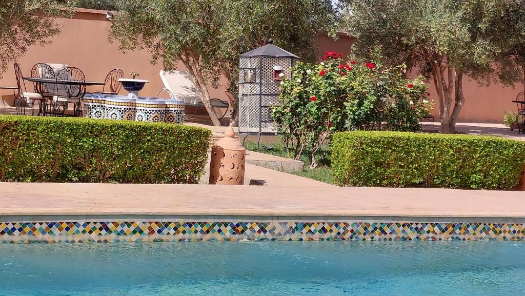 una piscina con tavolo, panca e fiori di Riad Dar Chenguiti a Taroudant