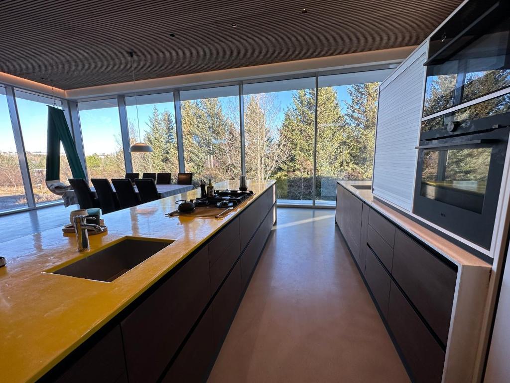 a kitchen with a long counter with chairs and windows at Villa by the lake Elliðavatn - Birta Rentals in Reykjavík