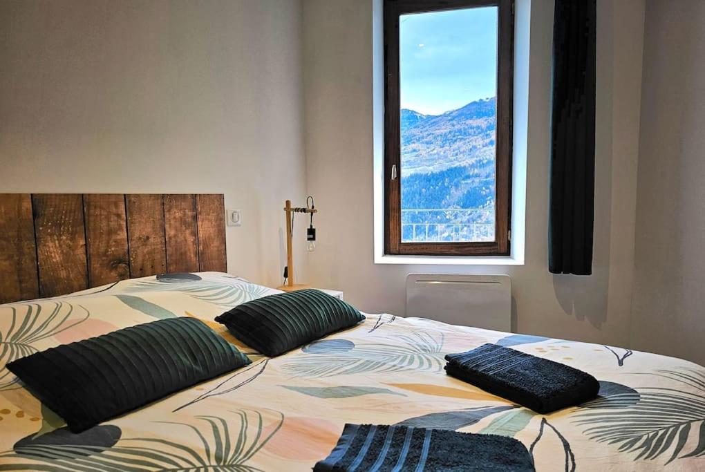 a bed with two pillows on it with a window at Appartement de 80m² plein sud entièrement rénové in Aime La Plagne