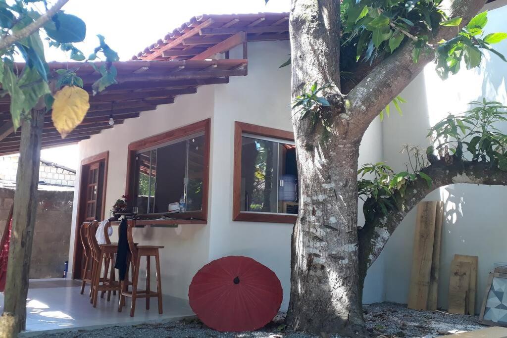 een huis met een rode paraplu naast een boom bij Loft da Árvore nas Falésias em Cumuruxatiba in Prado