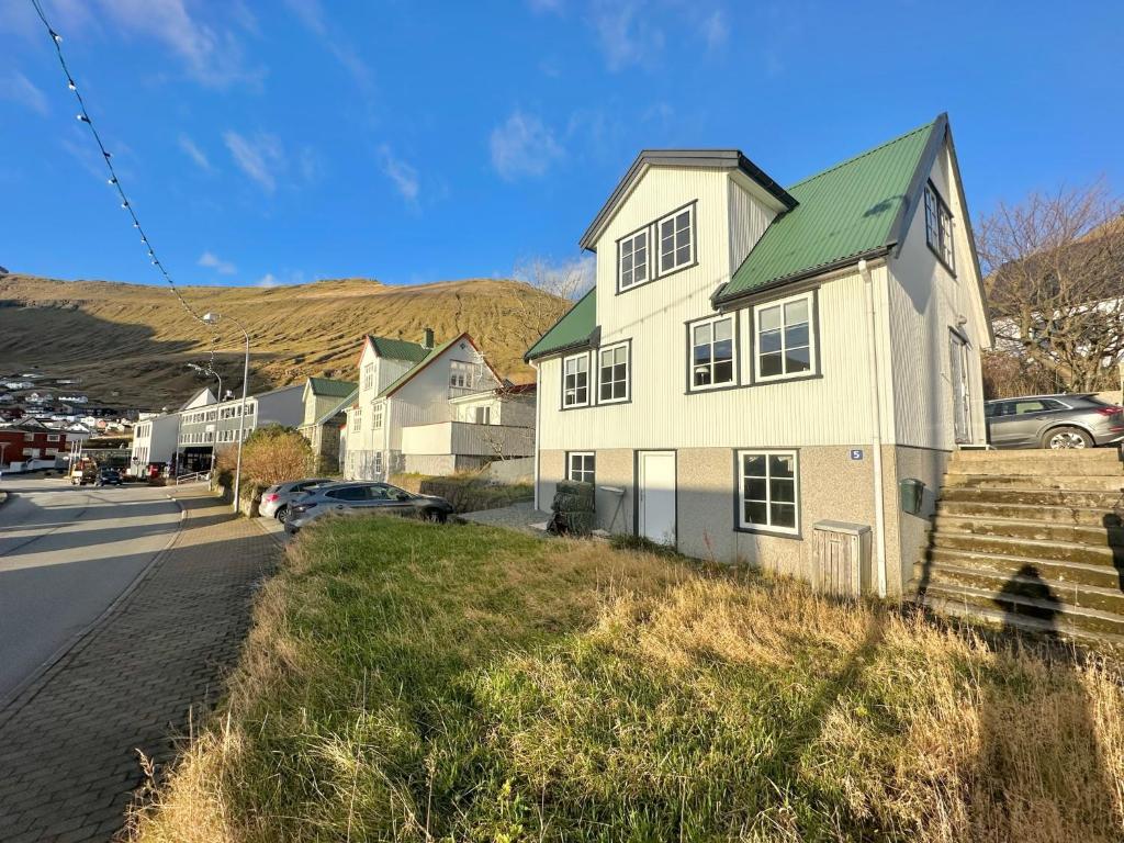 uma casa branca com um telhado verde numa rua em House in Fuglafjørður em Fuglafjørður