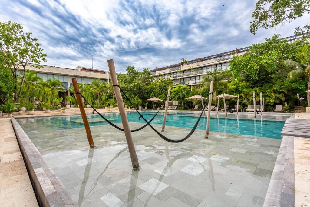 a swimming pool with umbrellas in front of a building at Luxury Stay at AWA Playacar 3BR Designer Condo in Playa del Carmen
