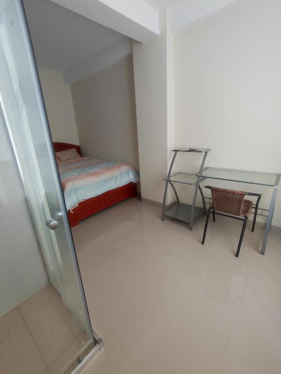 um pequeno quarto com uma cama e uma mesa de vidro em Apartments em Chiclayo