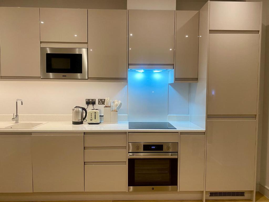 een keuken met witte kasten en een fornuis met oven bij Modern & Luxury Flat in Sutton