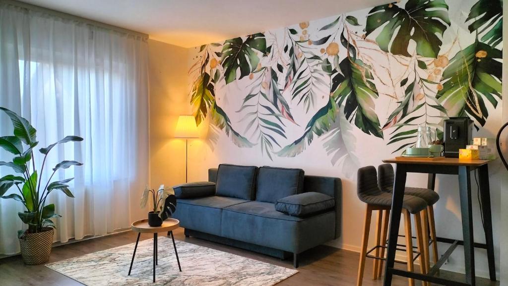 a living room with a blue couch and a plant mural at King Bed 4 people near Basel, Switzerland, Weil am Rhein, Loerrach, Germ'any, Near Airport in Saint-Louis