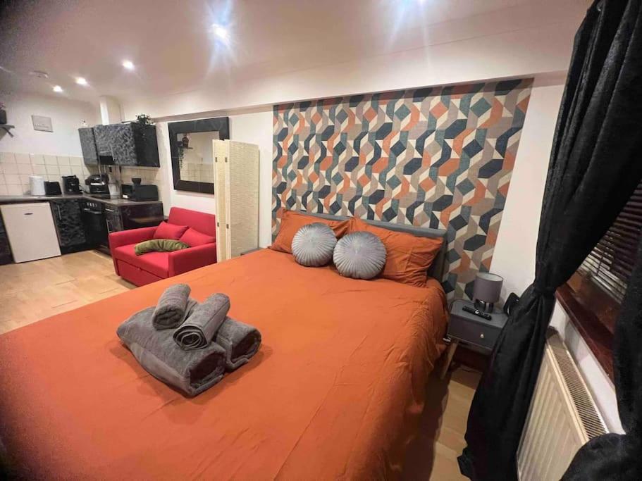 a bedroom with a large orange bed and a red chair at Nice StudioFLAT in London in London