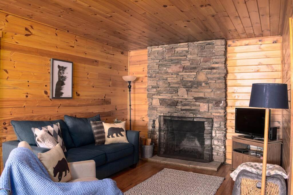 a living room with a blue couch and a stone fireplace at Nantahala Resort cabin, POOL OPEN, horseback riding, game room, gym, restaurant on site in Bryson City