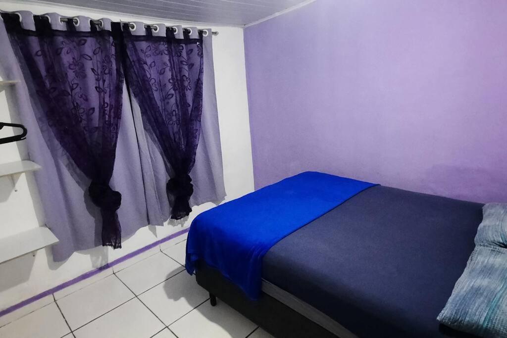 a bedroom with a blue bed and purple curtains at Casa dos Sonhos in Campo Grande