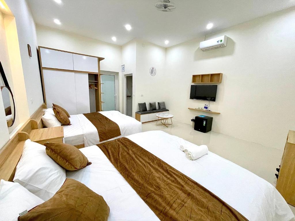 una camera d'albergo con tre letti e una televisione di GREEN HOTEL a Cao Bằng