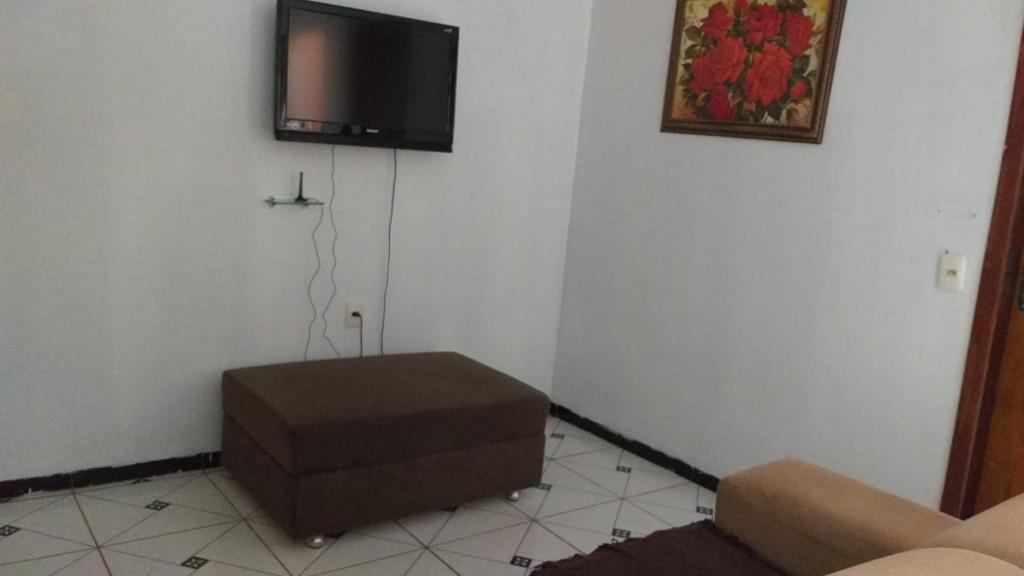 uma sala de estar com um sofá e uma televisão na parede em Doce Lar - 1 suíte em Tangará da Serra