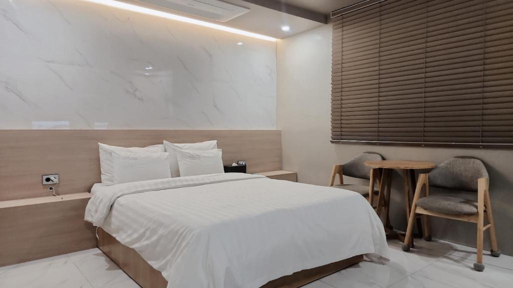 1 dormitorio con 1 cama, mesa y sillas en Shire Hotel Busan Station en Busan