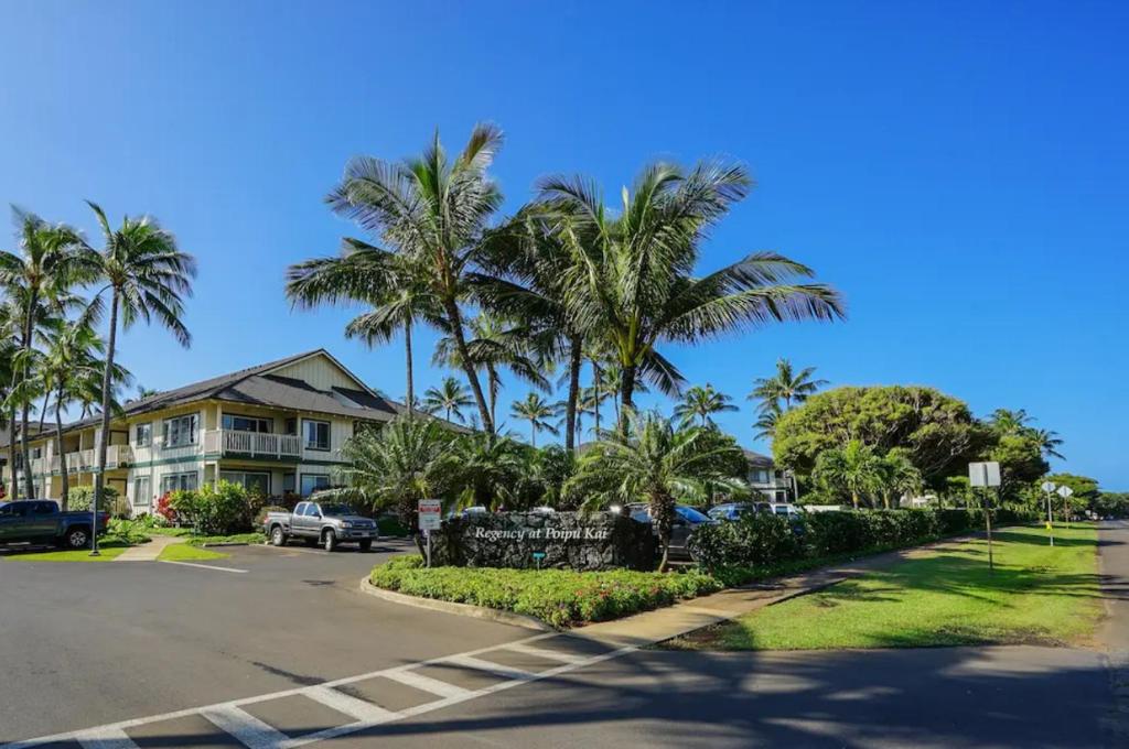 a street with palm trees in front of a house at Poipu Kai - Koloa, HI in Koloa