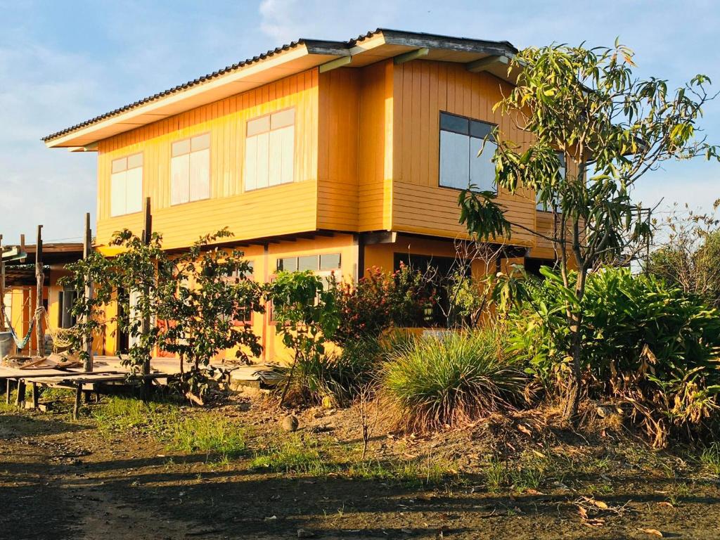 una casa amarilla con una mesa delante en The Orange House Thailand - Baan P'Nae Homestay, en Ban Khlong Bang Khrok