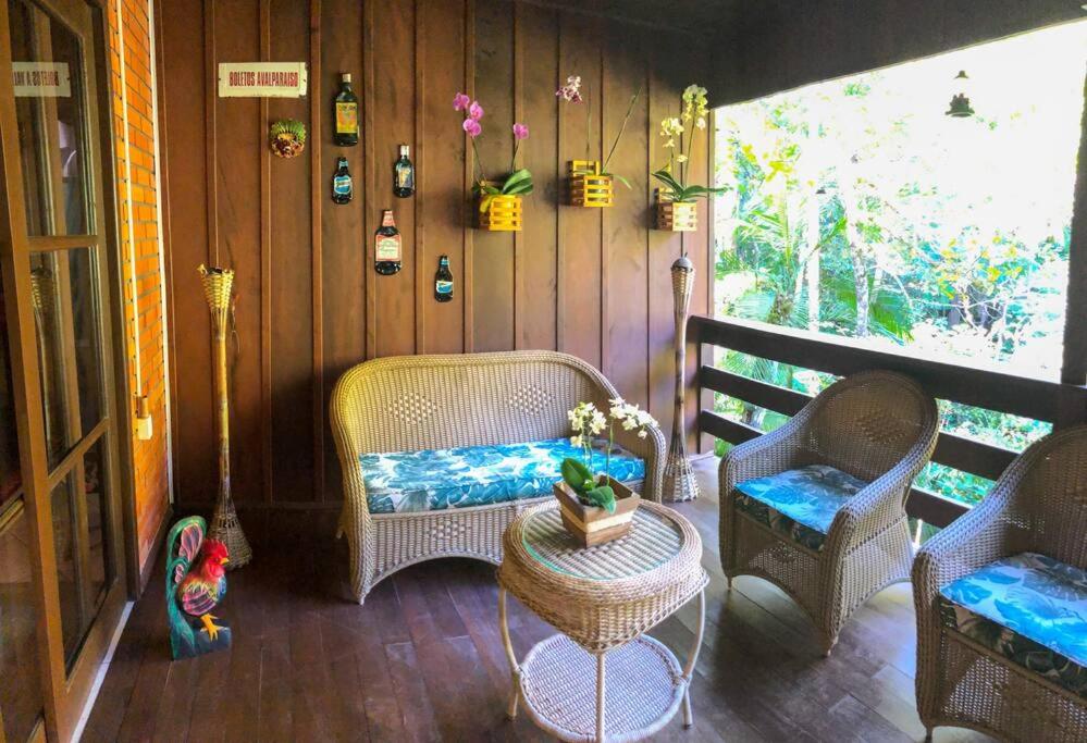 a porch with wicker chairs and a table at Casa de campo com cachoeira no quintal in Gaspar