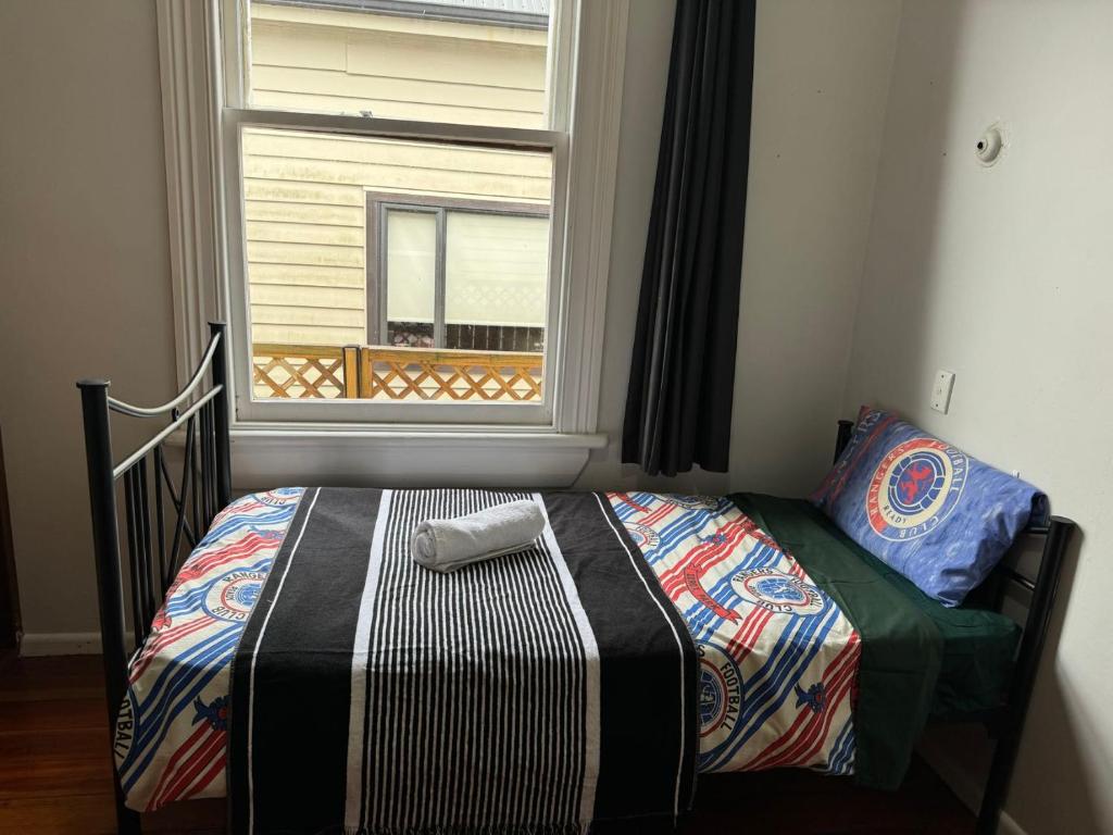 a bed sitting in a room with a window at Mt Eden Tidy Bedroom rm7 in Auckland