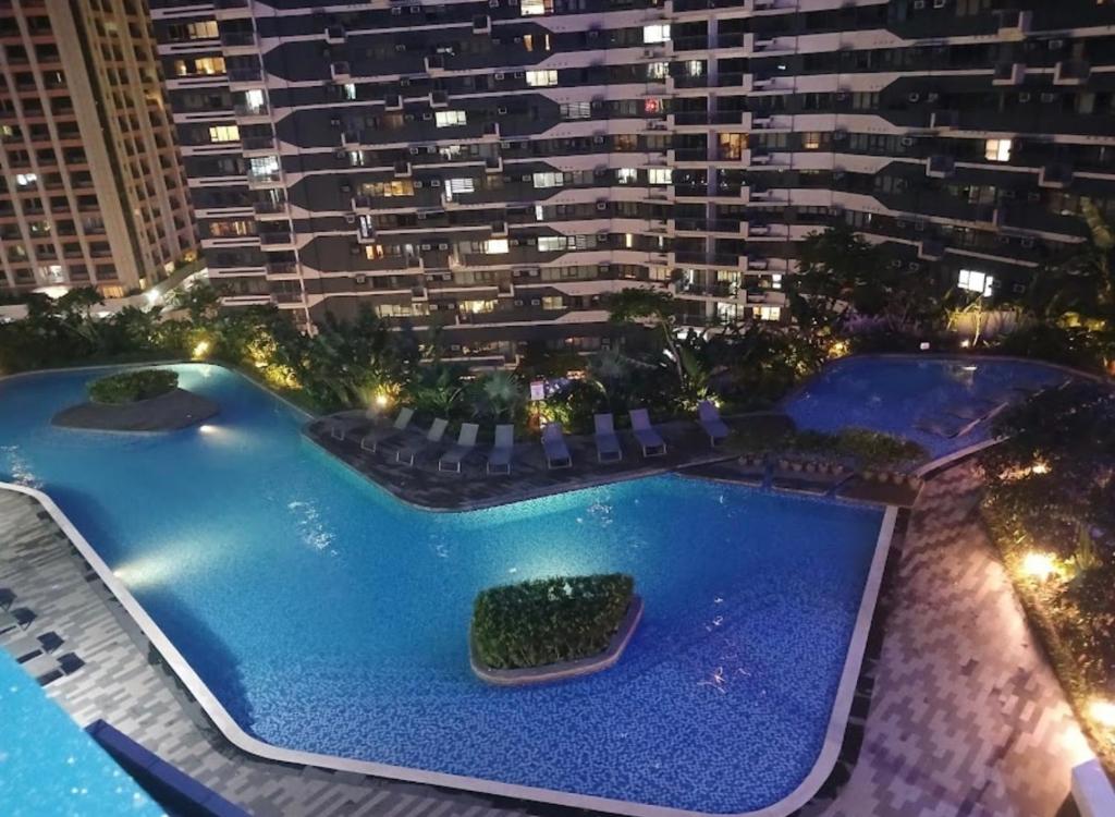 una vista de dos piscinas por la noche con un edificio alto en Luxurious stay at Air Residences, en Manila