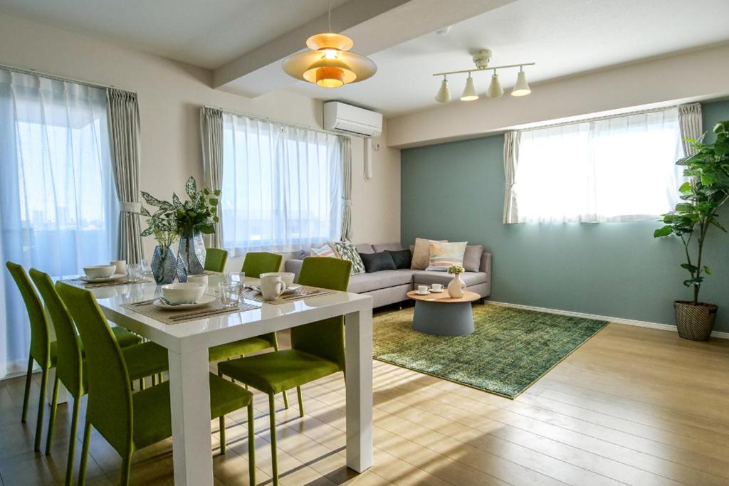 sala de estar con mesa blanca y sillas verdes en Premium Apartment Hotel Tokyo East en Tokio