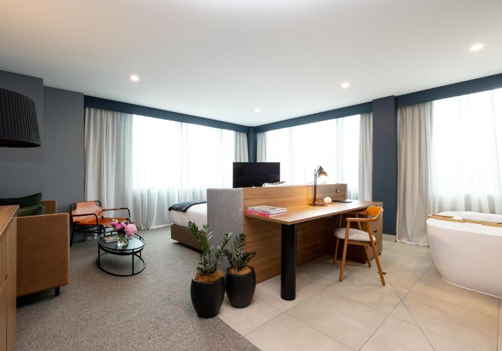 a hotel room with a desk and a bedroom at Sudima Auckland City in Auckland