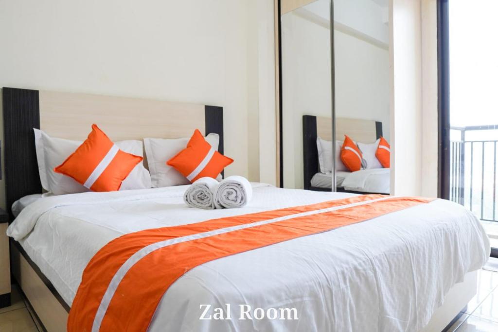 een slaapkamer met een groot bed met oranje en witte kussens bij AzzaRoom panoramic in Bandung